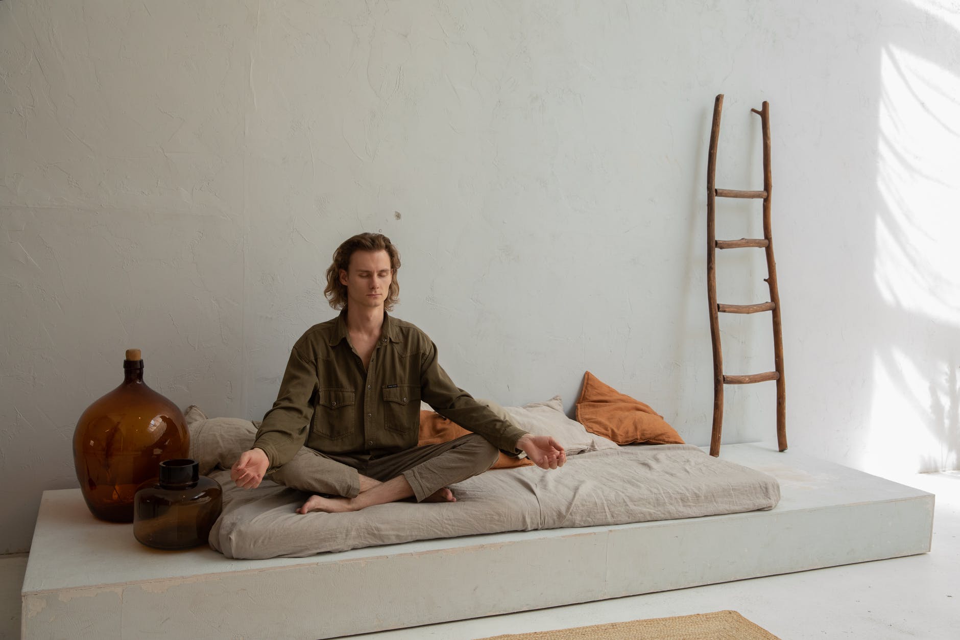 peaceful man meditating on bed in lotus pose
