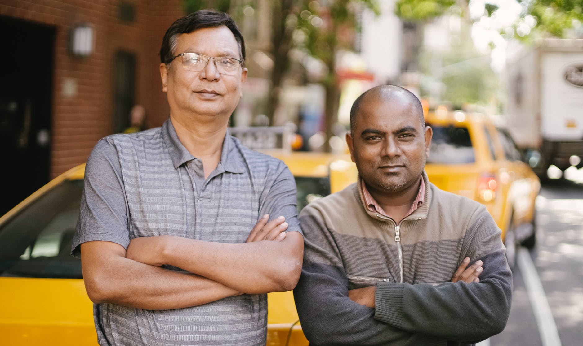 confident diverse taxi drivers with crossed arms on urban road