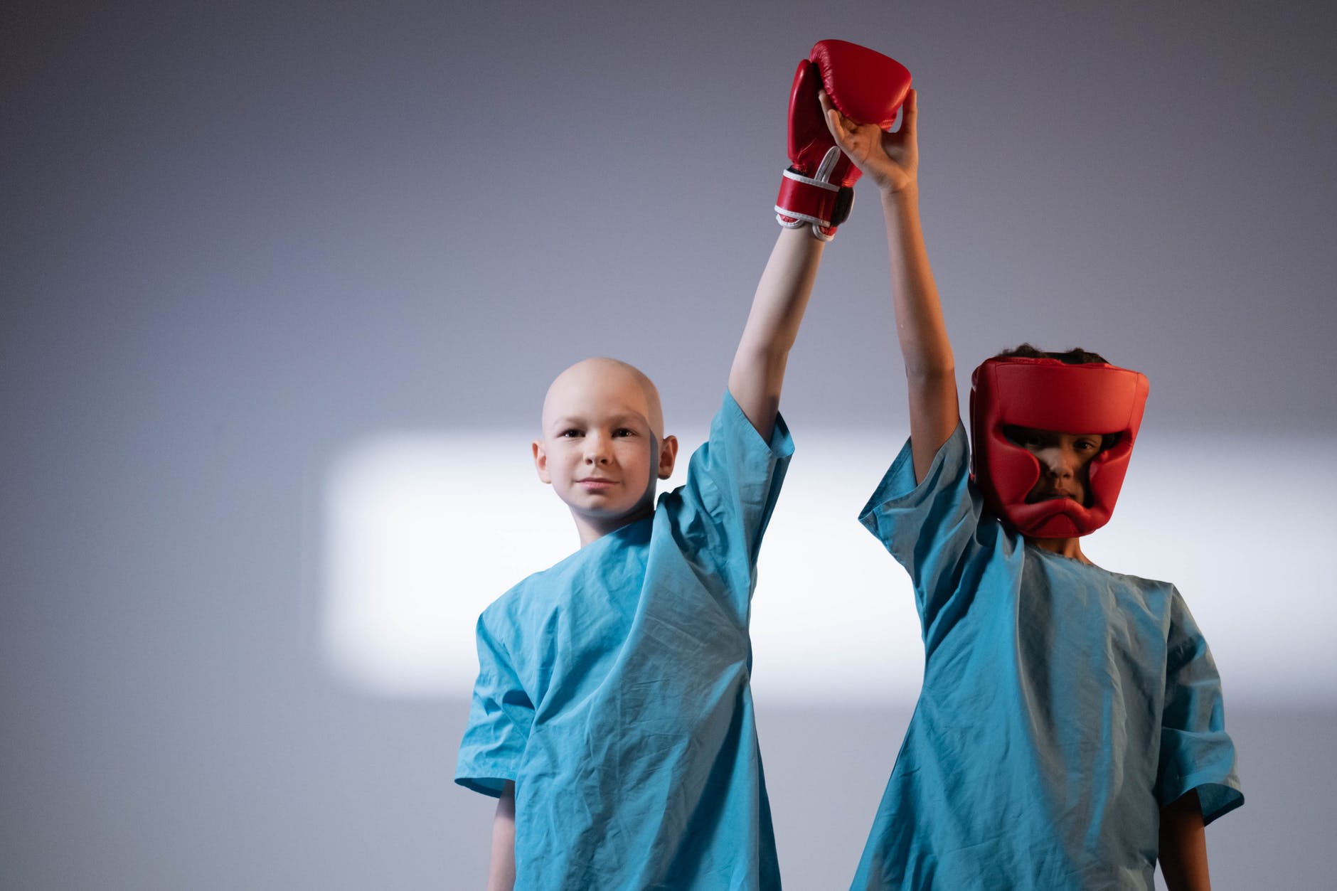 boy in blue lab gown wearing red boxing gloves