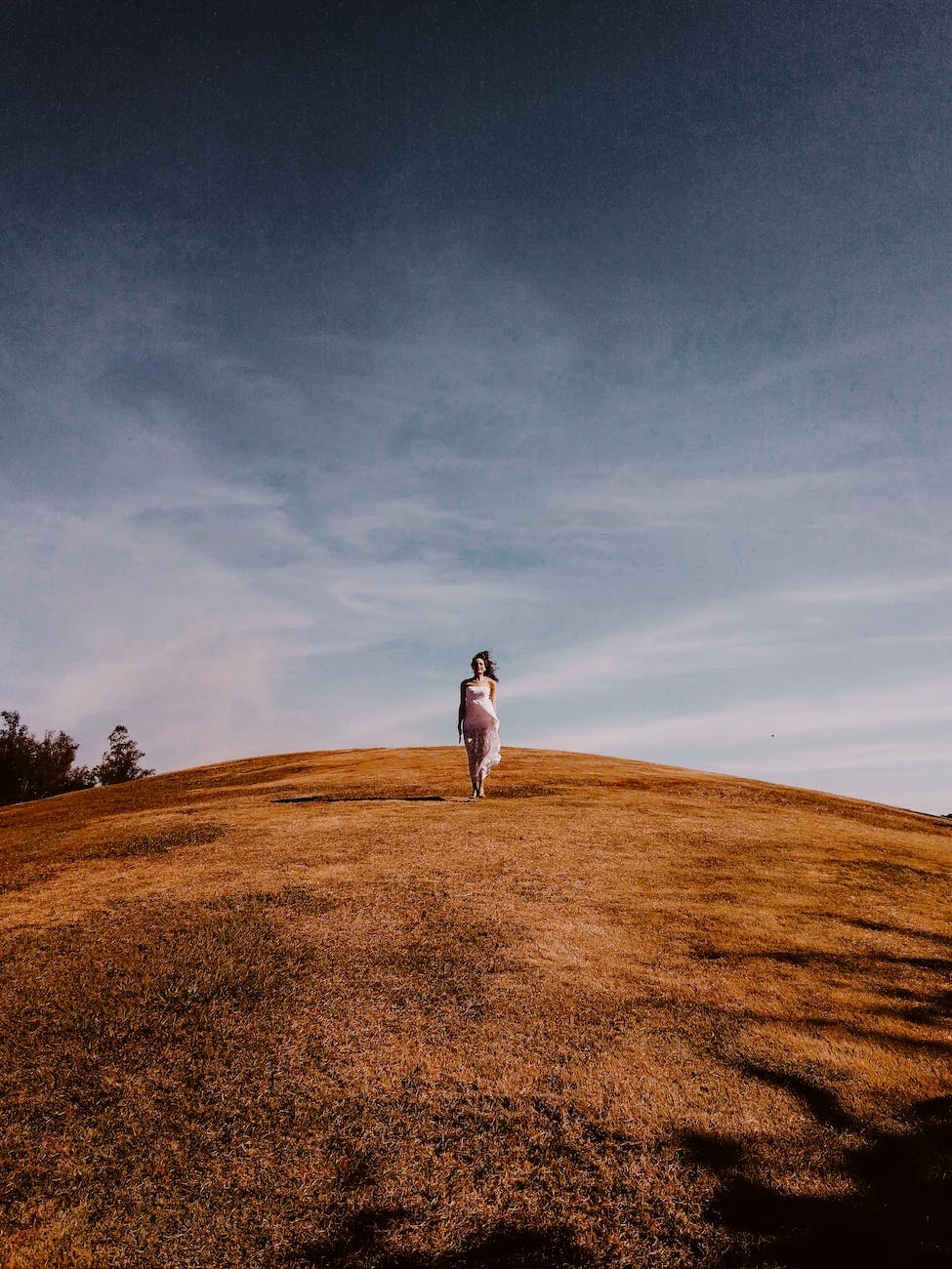 photo of woman standing on grass hill